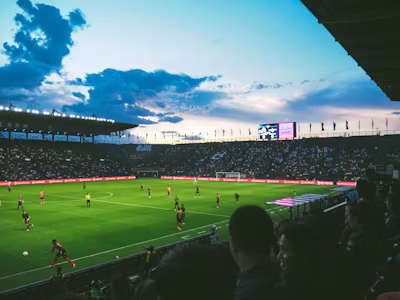 A floodlit football stadium drawing tens of thousands of fans